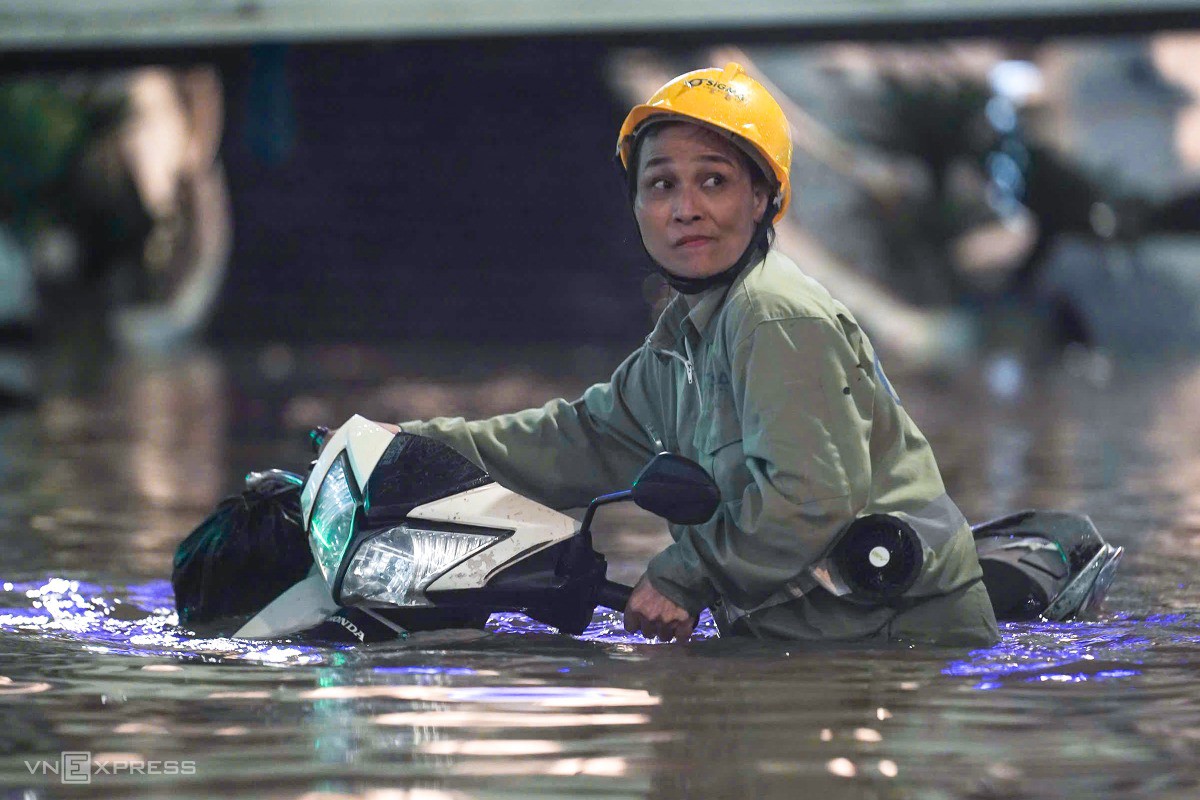 Người dân dắt xe chết máy giữa đường Láng Hạ - Thái Hà ngập gần 1 mét. Ảnh: Hoàng Giang