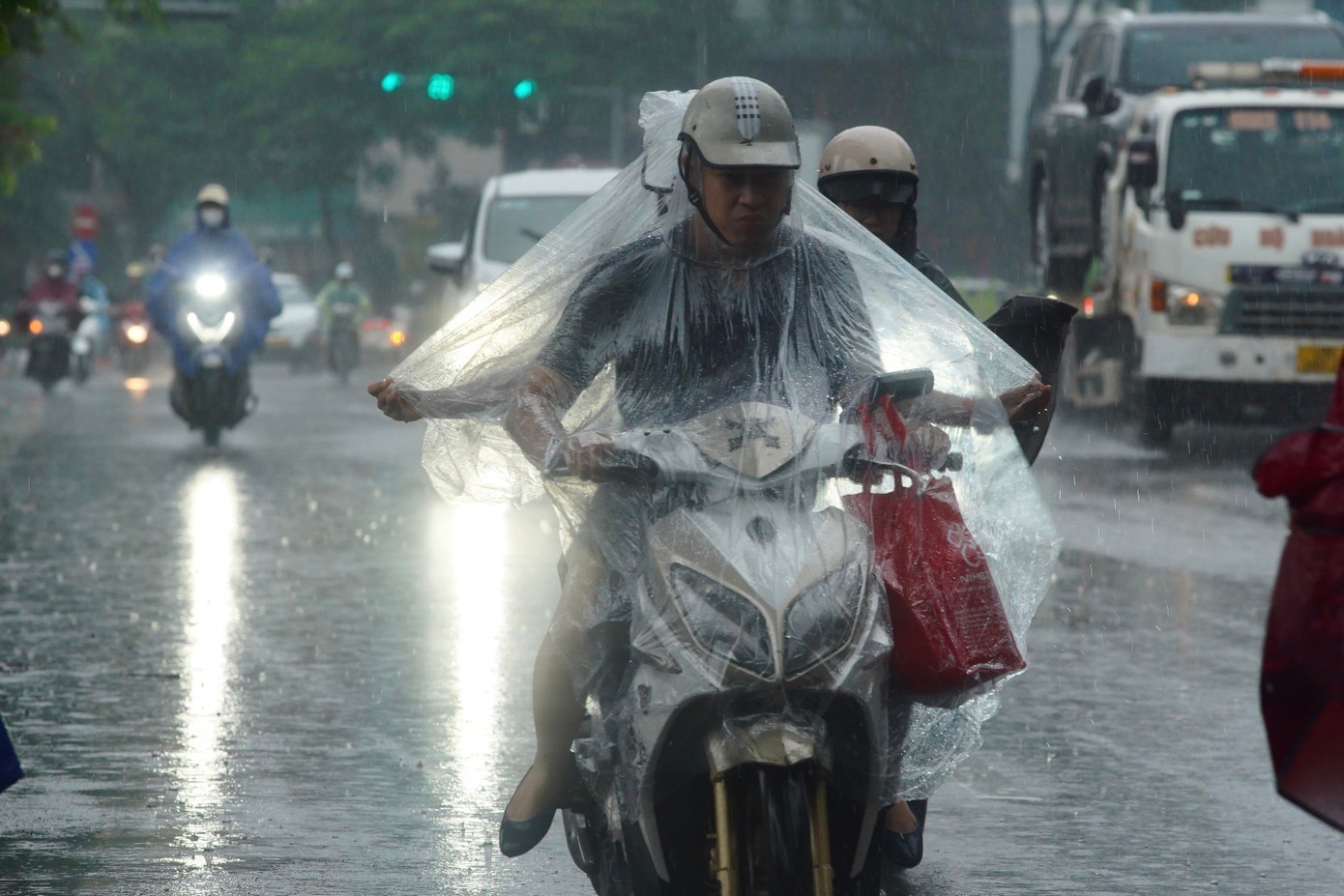 Các phương tiện xe máy di chuyển khó khăn dưới bầu trời tối và mưa lớn.