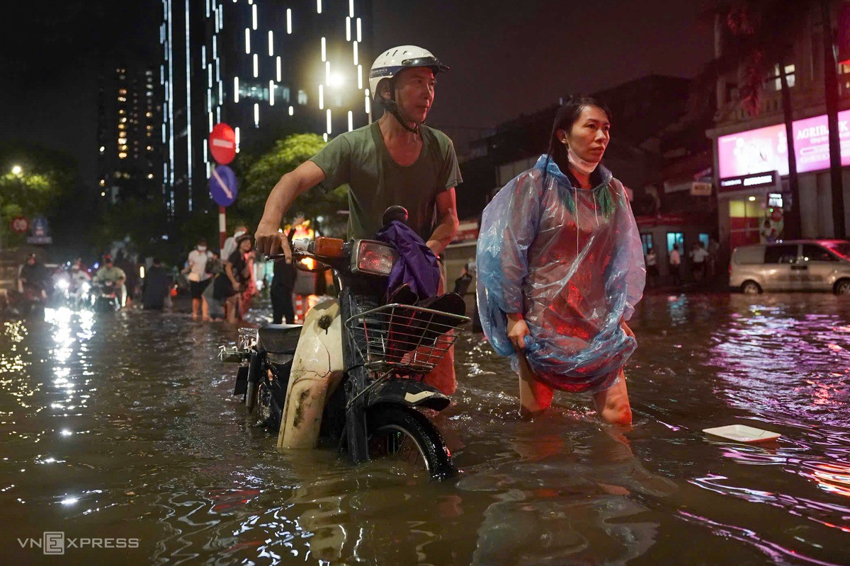 Người dân mệt mỏi khi phải đẩy xe chết máy trên đường ngập nước. Ảnh: Hoàng Giang