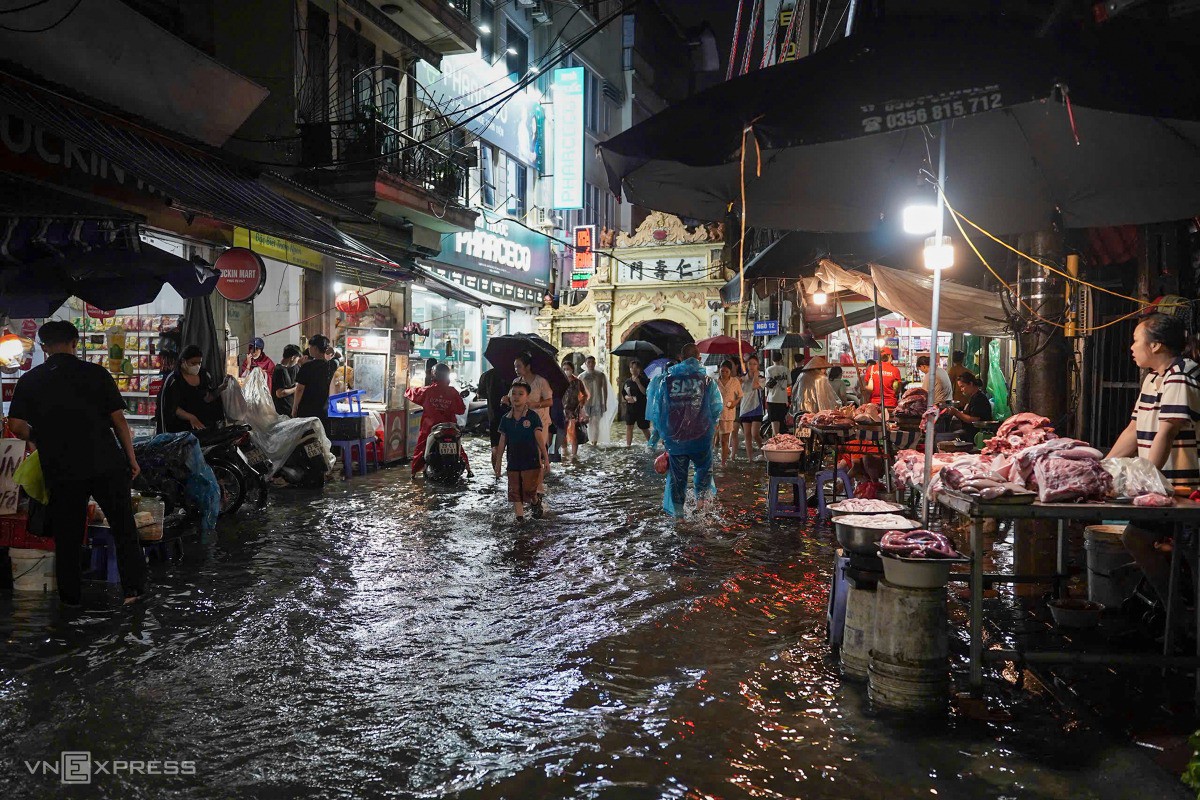 Người dân lội nước đi mua thực phẩm về nấu ăn tối. Ảnh: Hoàng Giang