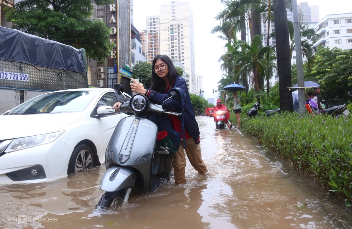 Học sinh dắt xe qua đoạn ngập trên phố Hàm Nghi. Ảnh:&nbsp;Phạm Dự