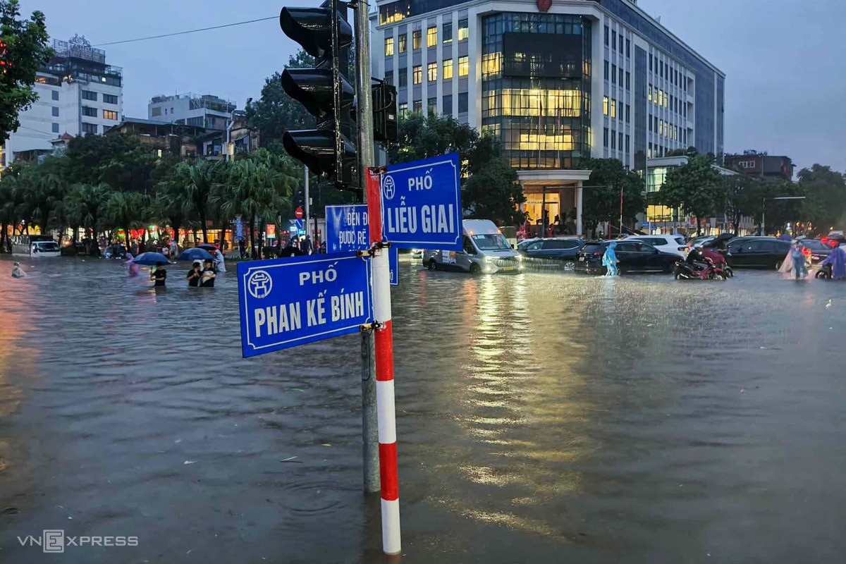 Người dân lội nước ngập nửa người, vất vả di chuyển trên phố. Ảnh: Văn Doanh