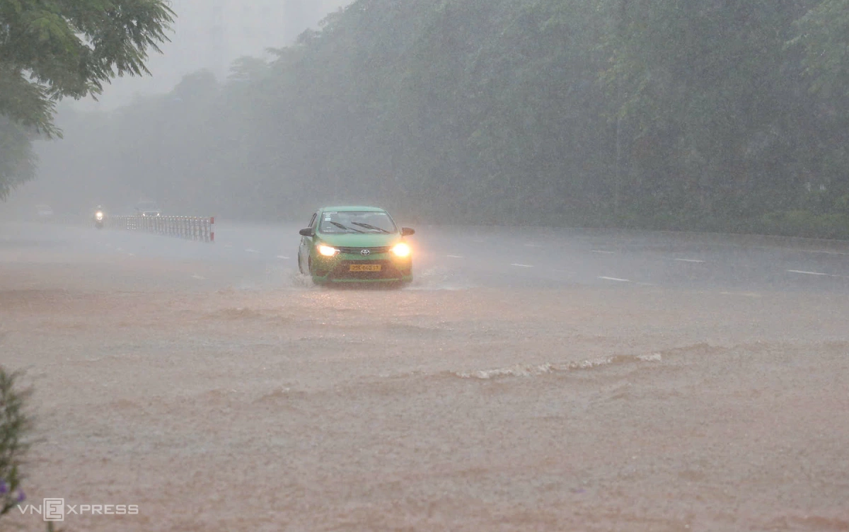 Chiếc taxi di chuyển qua đoạn ngập nước trên đường Võ Chí Công trong cơn mưa lớn. Ảnh:&nbsp;Phạm Chiểu