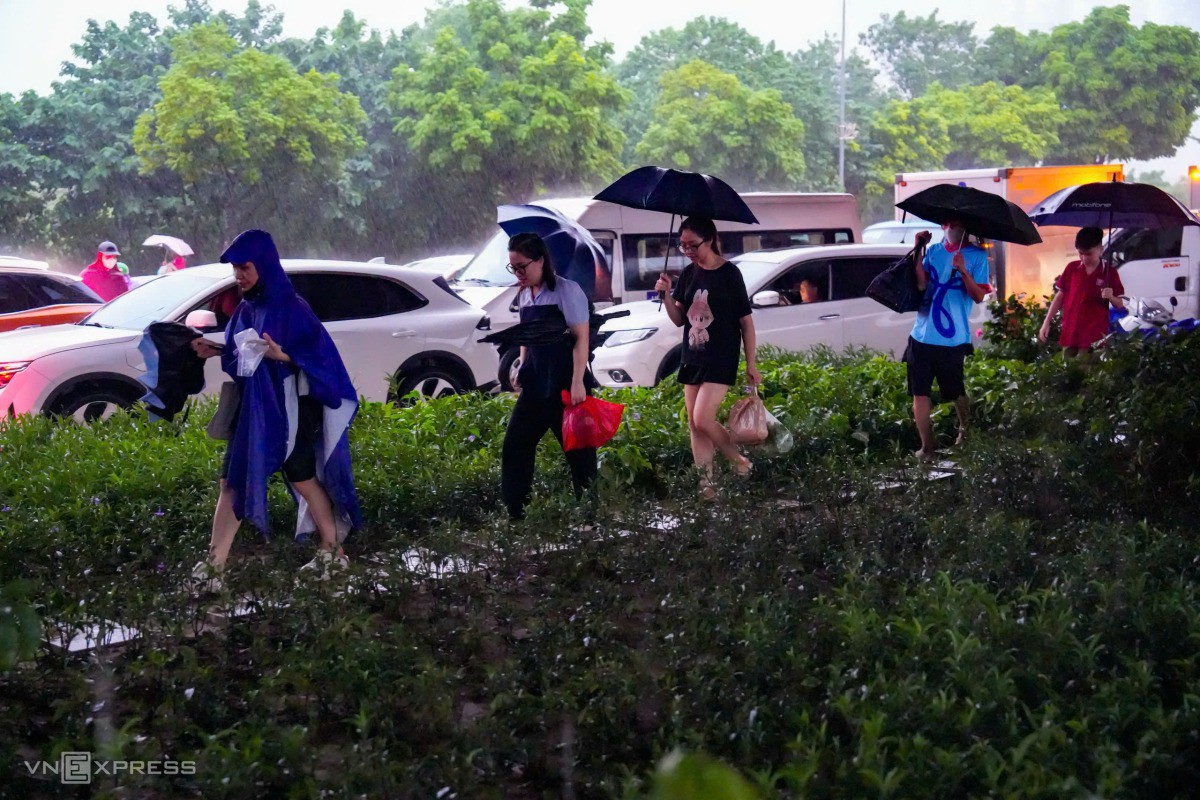 Người dân đi bộ trên dải phân cách vành đai 3 để tránh đoạn ngập. Ảnh: Tùng Đinh