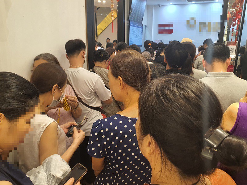 Mặc kệ giá vàng cao và thời tiết mưa bão, hàng trăm người vẫn chen chúc xếp hàng mua vàng.