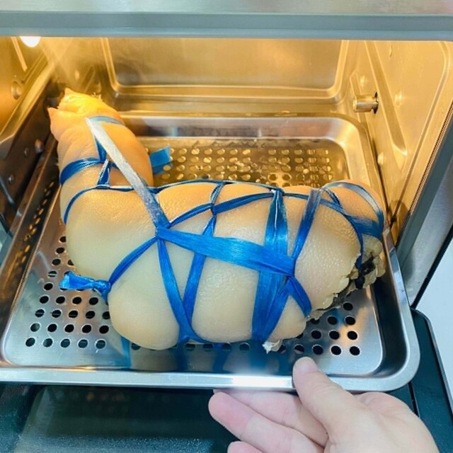Chân giò đã được nhồi, buộc chặt lại đem hấp bằng nồi chiên hơi nước. Ảnh:Thanh Huệ