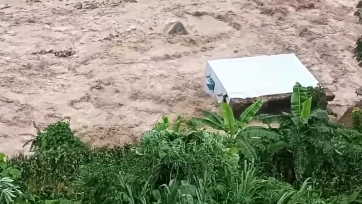 Căn nhà 2 tầng của gia đình anh Lý Văn Quang bị đổ sập xuống suối Nậm Lụm. Ảnh cắt từ clip