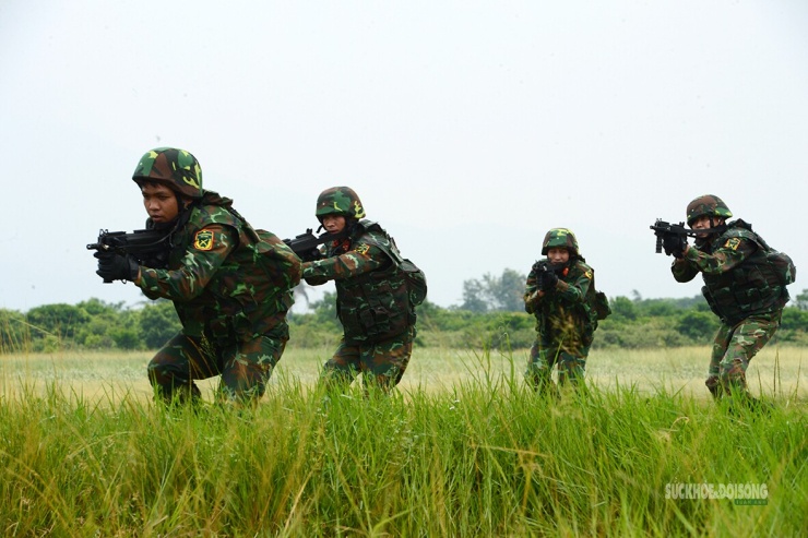Từng tổ chiến đấu cơ động qua khu vực trống, giữ đội hình và quan sát mục tiêu phía trước.