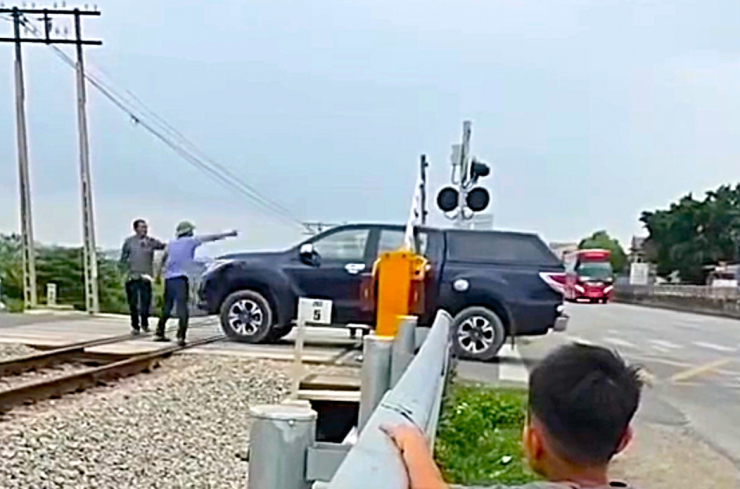 Hiện trường vụ nữ tài xế cố lái xe băng qua đường sắt khi rào chắn đã hạ ở Nghệ An. (Ảnh cắt từ video).