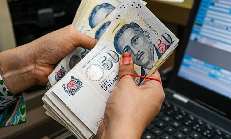 Một nhân viên đếm các tờ tiền đôla Singapore tại một quầy đổi tiền ở khu trung tâm tài chính Raffles Place tại Singapore ngày 06/10/2022. Ảnh: AFP