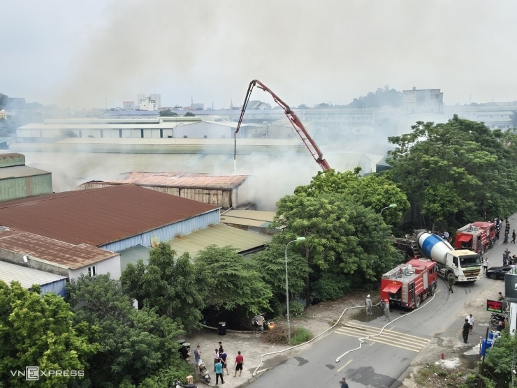 Lửa bùng lên khoảng 10h từ phòng sơn và gian gác xép dẫn lên phòng phun sơn của xưởng. Do chứa nhiều gỗ thành phẩm và nguyên liệu, đám cháy nhanh chóng lan mạnh, kèm nhiều tiếng nổ. Khoảng 30 công nhân bên trong chạy tán loạn. "Một phần mái xưởng bất ngờ sập, khiến nhiều người ngã đè lên nhau, một số không thể thoát ra", công nhân Trịnh Xuân Nghiêm, 25 tuổi, nói. 10 xe cứu hỏa cùng hàng chục cảnh sát chữa cháy Hà Nội được huy động, triển khai dập lửa. Từ đường Ngọc Hòa, lực lượng dùng vòi rồng phun nước và huy động cẩu xe trộn bêtông chọc thủng mái tôn, đưa nước vào trung tâm đám cháy. Ảnh: Vương Minh