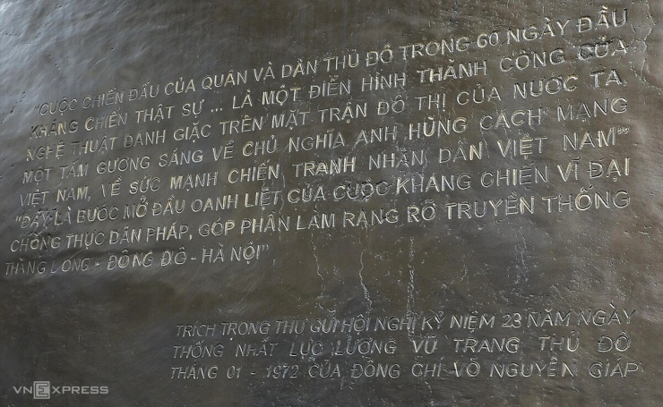 Mặt trước phù điêu khắc họa các chiến sĩ cảm tử quân ôm bom ba càng, hình ảnh biểu tượng cho 60 ngày đêm chiến đấu bảo vệ Thủ đô. Bên cạnh là hình ảnh bộ đội cầm súng, công nhân và phụ nữ Hà Nội sát cánh cùng các chiến sĩ. Phía sau là những mái nhà phố cổ, chợ Đồng Xuân và ô Quan Chưởng xưa. Mặt sau phù điêu khắc đoạn trích trong thư đại tướng Võ Nguyên Giáp gửi Hội nghị kỷ niệm 23 năm Ngày Thống nhất lực lượng vũ trang Thủ đô, tháng 1/1972.
