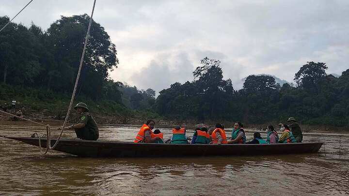 Lực lượng chức năng giăng dây, chèo thuyền đưa học sinh, các thầy cô qua sông. (Ảnh: Công an xã Yên Hòa)