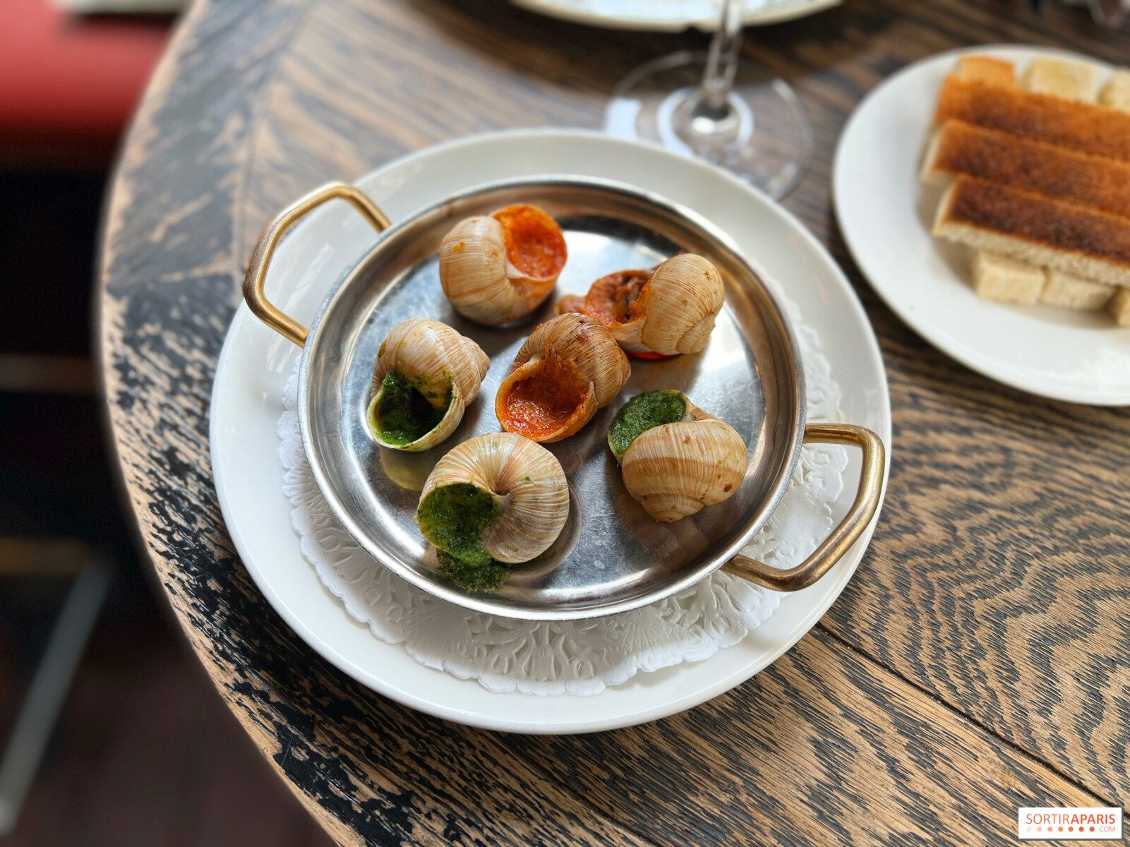 Ốc sên được phục vụ cùng bánh mì và rượu vang tại nhà hàng L’Escargot Montorgueil.Ảnh: Manon de Sortiraparis/Sortir à Paris.