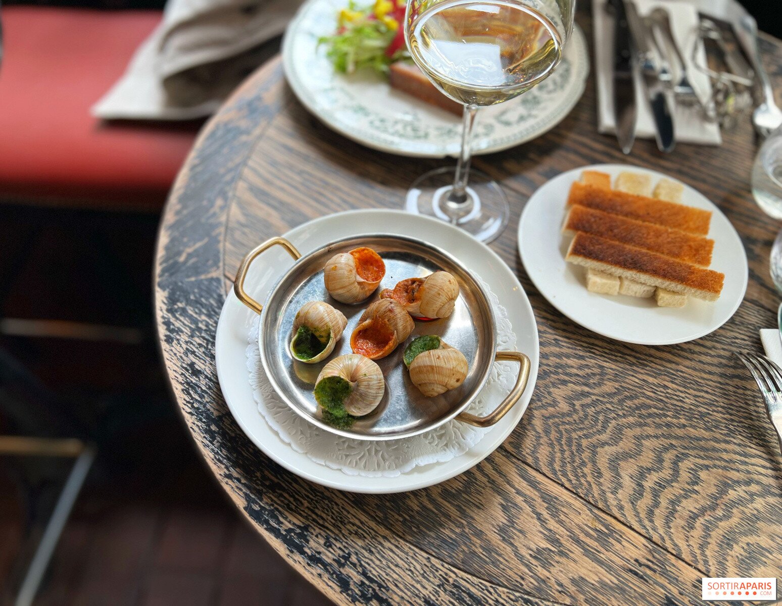 Ốc sên được phục vụ cùng bánh mì và rượu vang tại nhà hàng L’Escargot Montorgueil.Ảnh: Manon de Sortiraparis/Sortir à Paris.