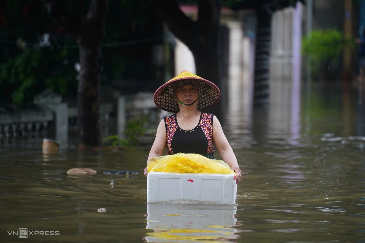 Người phụ nữ cho hàng vào thùng xốp, lội bộ giữa phố Cầu Cốc. Ảnh: Hoàng Giang