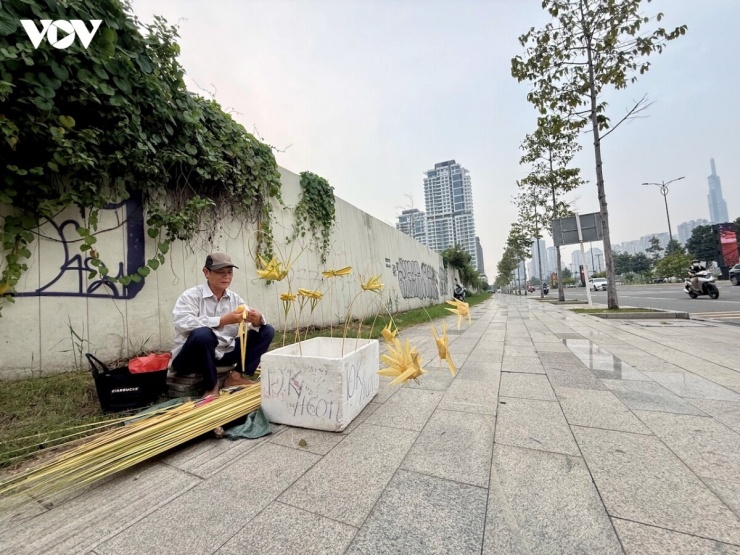 Ông Đoàn Mạnh Hùng bên “cửa hàng” nhỏ trên hè với công việc đan đồ chơi bằng lá dừa suốt hai thập kỷ.