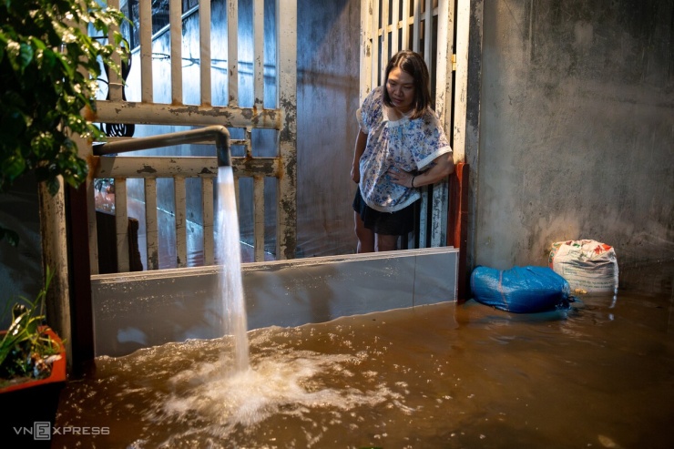 Người dân ở ngõ 200 Âu Cơ bơm nước ra khỏi nhà, chờ dọn dẹp. Khu vực này còn ngập hơn nửa mét.