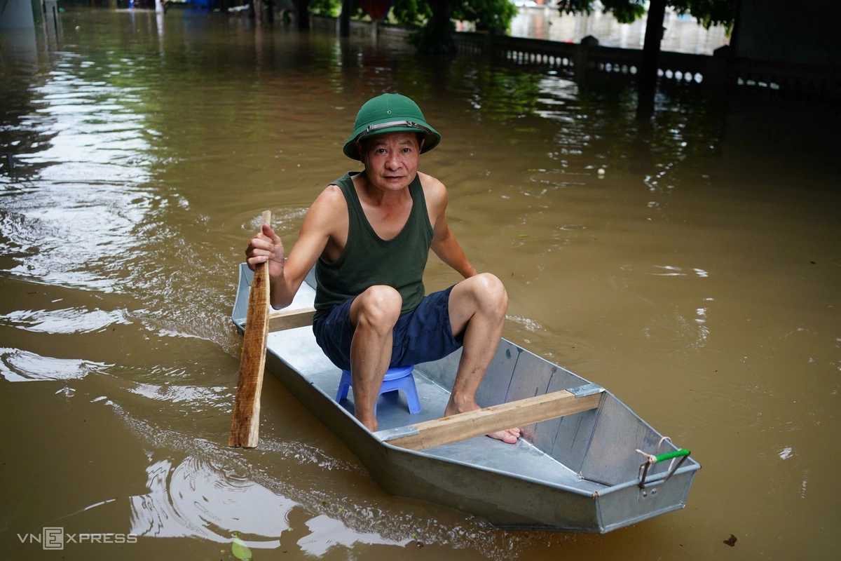 Do phố ngập sâu, người đàn ông dùng thuyền mua thực phẩm cho gia đình. Ảnh: Hoàng Giang