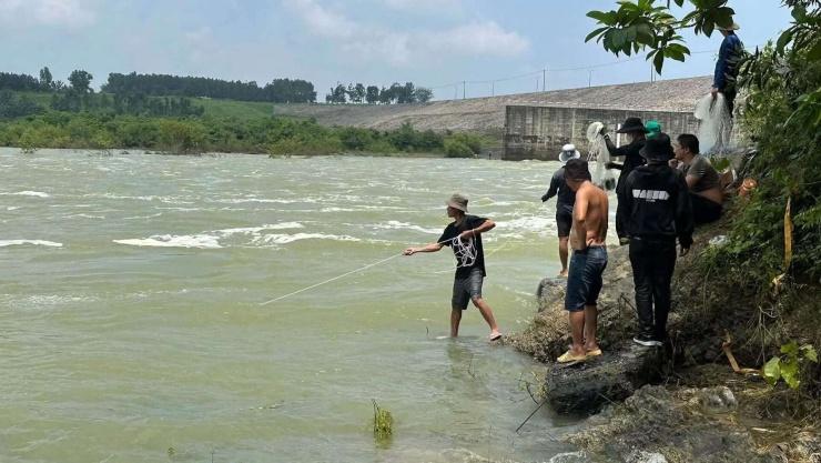 Kế bên chân đập, một số người dựng lều, ngồi nghỉ, mang chài lưới ra sát mép nước chờ đánh cá. Ảnh: TAQT