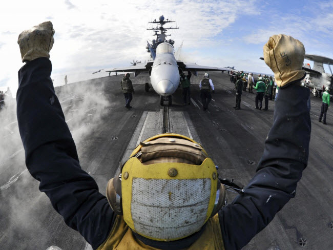 Một binh sĩ chỉ dẫn chiến đấu cơ F/A-18C Hornet vào bệ phóng trên tàu sân bay USS Harry S. Truman.
