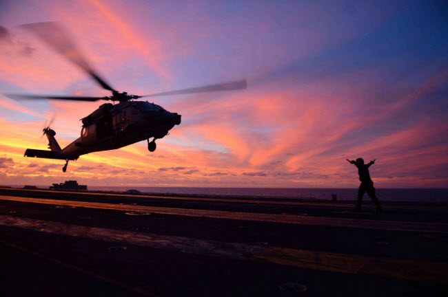 Máy bay trực hạ cánh xuống tàu sân bay USS John C. Stennis lúc hoàng hôn.