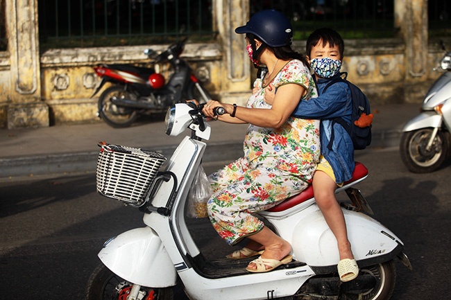 Trẻ em đi học buổi sáng chỉ khoác chiếc áo mỏng, nhưng vẫn mặc quần đùi.