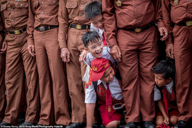 Các cậu bé học sinh Tiểu học tò mò chui qua hàng của cựu chiến binh tại một sự kiện ở Indonesia. Ảnh: Donny Herry