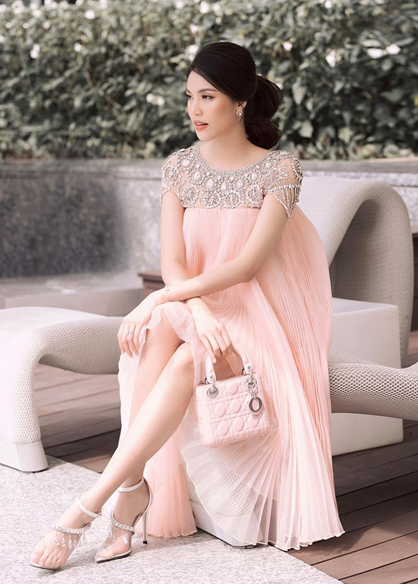 Dù đang ở những tháng cuối của thai kỳ như Lan Khuê vẫn luôn chứng minh rằng bầu bí cũng không hề ảnh hưởng đến sự sành điệu và thời thượng của cô. Trong chiếc váy xếp li màu hồng nude với phần vai được đính kết cầu kỳ, Lan Khuê khoe nhan sắc rực rỡ và kiêu kỳ. Cô chọn thêm chiếc túi Dior Lady và đôi giày trong suốt để tạo nên một tổng thể hài hòa.