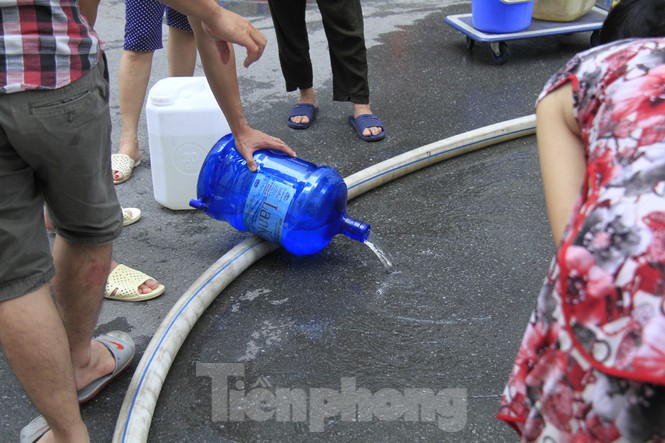 Một số người đổ bỏ lượng nước vừa lấy từ xe téc 29C-192.81 tại chung cư Linh Đàm (Ảnh: Tiền Phong)