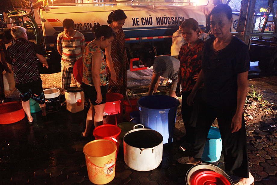 Người dân mang xếp hàng lấy nước sạch từ xe téc trong đêm 16/10. Ảnh: Hồng Phú