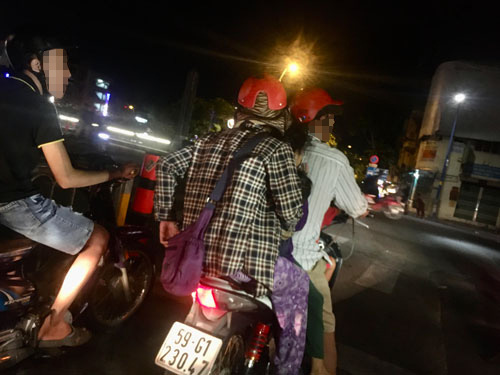 Người phụ nữ mặc áo carô và 3 đứa trẻ được người đàn ông đón về khu nhà trọ tại phường 16, quận 8, sau một ngày “hành nghề”. Ảnh: PHƯƠNG TRINH