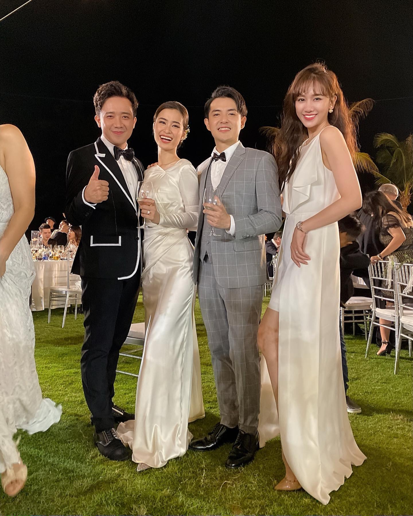 Hari Won cũng chọn mặc váy hai dây với thiết kế phần trước ngắn, phía sau dài cùng chi tiết được may bằng vải xuyên thấu trước ngực. Trong khi đó Trấn Thành lịch lãm với vest đen, tạo điểm nhấn bằng một vài đường may viền áo màu trắng. 