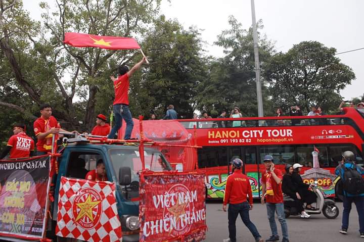 CĐV tươi cười vẫy cờ chào những vị khách du lịch ngoại quốc khi di chuyển qua khu vực hồ Hoàn Kiếm.