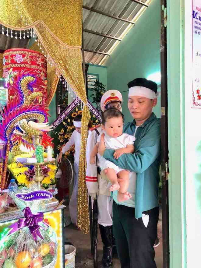 Người thân ẵm cháu bé 6 tháng tuổi, con Trung úy Tân trước quan tài cha