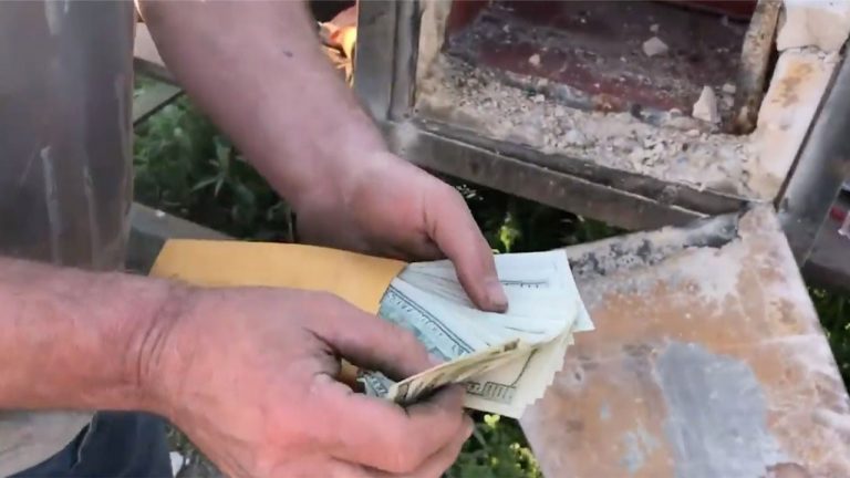 Phong bì chứa xấp tiền 100 USD khiến hai cha con kinh ngạc.