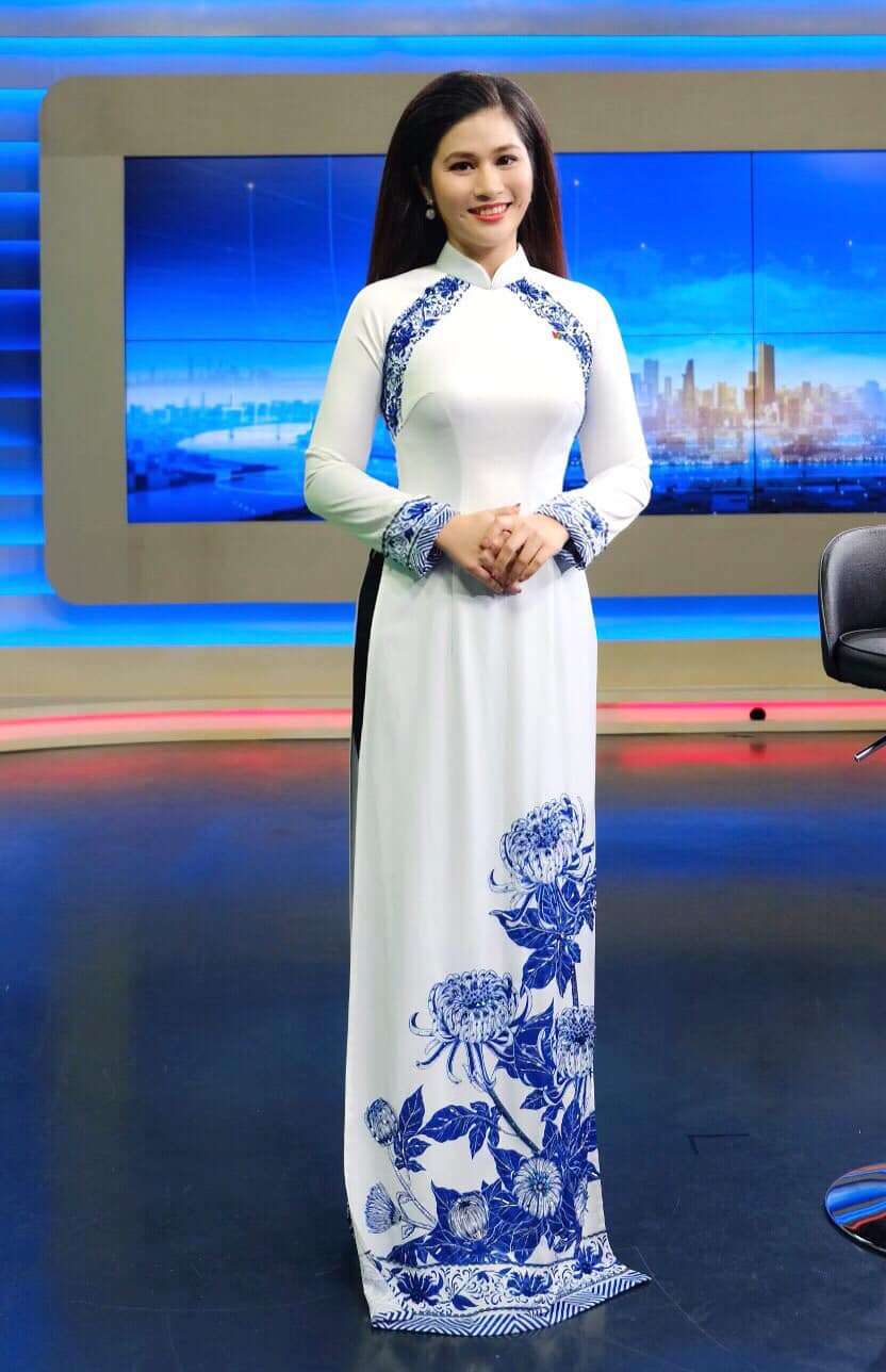 Bộ áo dài nhã nhặn với hai gam màu xanh, trắng và họa tiết hoa cúc của MC Minh Trang.