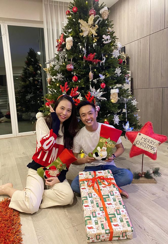 Đàm Thu Trang khéo léo dùng quà Giáng sinh che vòng 2 khi chụp ảnh cùng chồng.