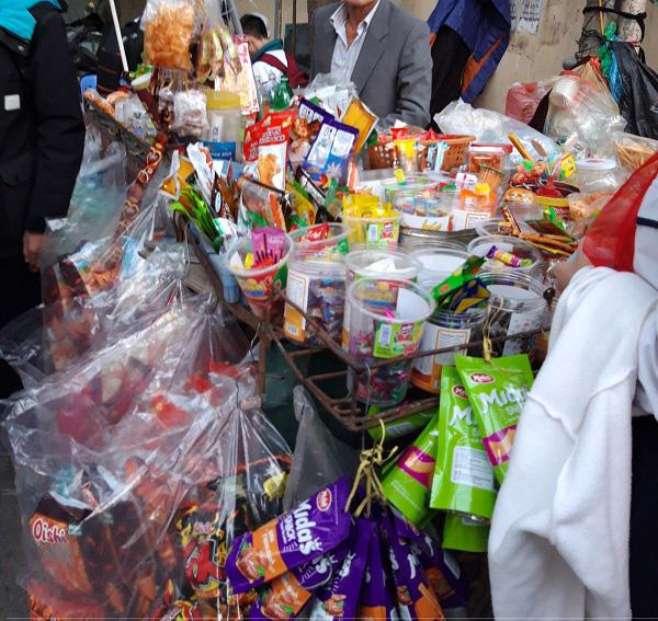 Tại một xe kéo hàng rong có rất nhiều loại đồ ăn vặt dành cho học sinh.
