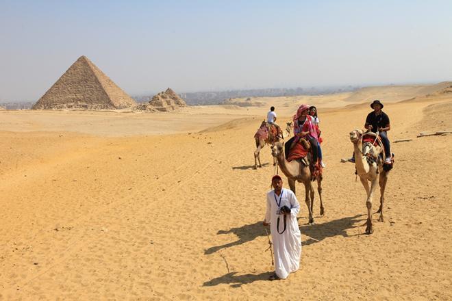 Khách du lịch cưỡi lạc đà tham quan Kim tự tháp Giza.