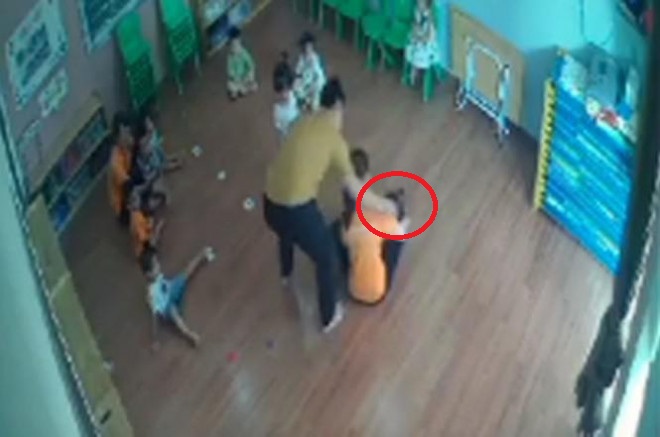 Người đàn ông có hành động túm tóc, đánh vào mặt bé gái 2 tuổi vì tranh giành đồ chơi với con mình. Ảnh cắt từ video.