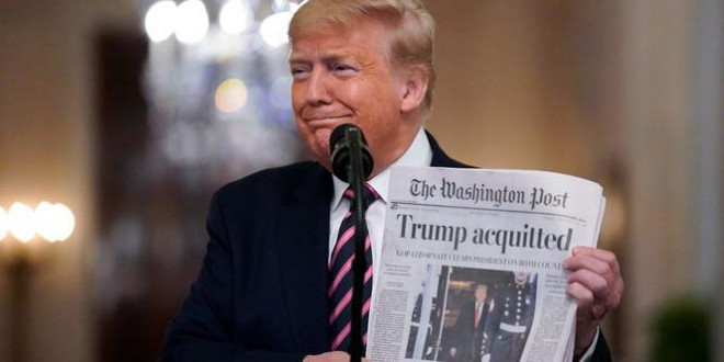 Tổng thống cầm tờ báo có bài "Ông Trump trắng án". Ảnh: AP