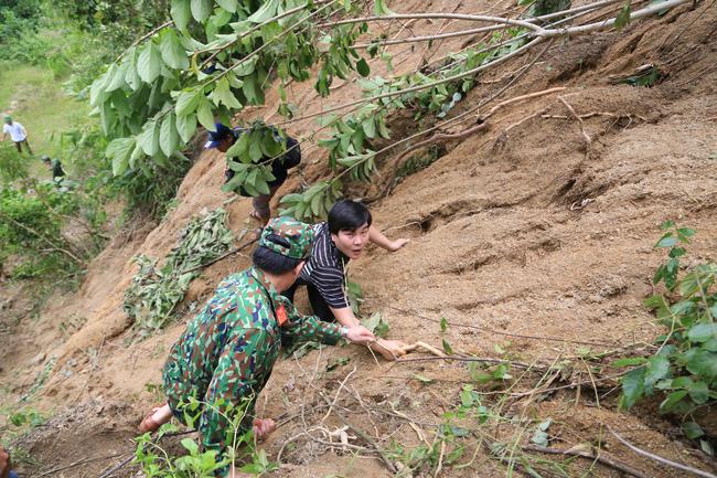 Bộ đội và phóng viên bám cây, leo dốc để vào điểm sạt lở ở xã Phước Lộc. Ảnh: P.V