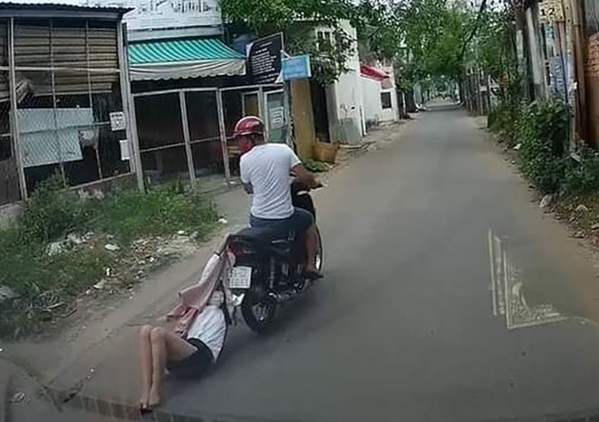 Sau khi cướp giật tài sản, đối tượng chạy xe máy đã kéo lê cô gái trên đường hàng trăm mét (ảnh cắt từ clip)