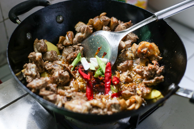 Dịch chuyển các miếng thịt ra xung quang thành chảo, tạo thành một chỗ trống ở giữa sau đó thêm tương đậu, ớt khô và hành lá, chiên trong 1 phút sau đó trộn đều tất cả lên.