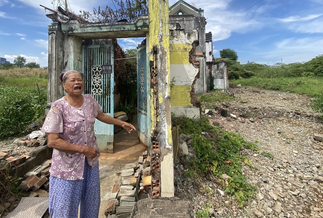 Bà Nguyễn Thị Giáp (80 tuổi) bên căn nhà bị đập loang lổ và lau sậy cao lút đầu người ở Thủ Thiêm