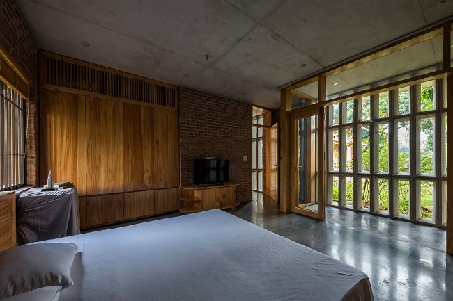 Phòng ngủ chính ở tầng 1 vẫn sử dụng chất liệu gỗ xoan chủ đạo, trần bê tông xám hài hòa vói khoảng sàn cũng bằng bê tông nhưng được đánh bóng.
