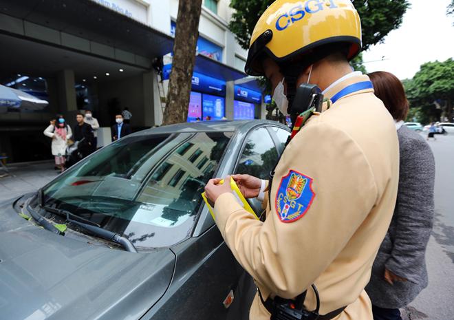 Lực lượng CSGT Hà Nội lập biên bản, dán thông báo "phạt nguội" đối với phương tiện vi phạm.