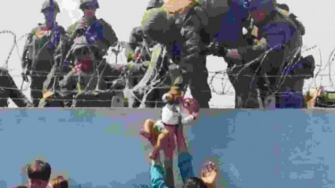 Cảnh lính Mỹ cứu bé gái 16 ngày tuổi qua hàng rào sân bay Kabul.