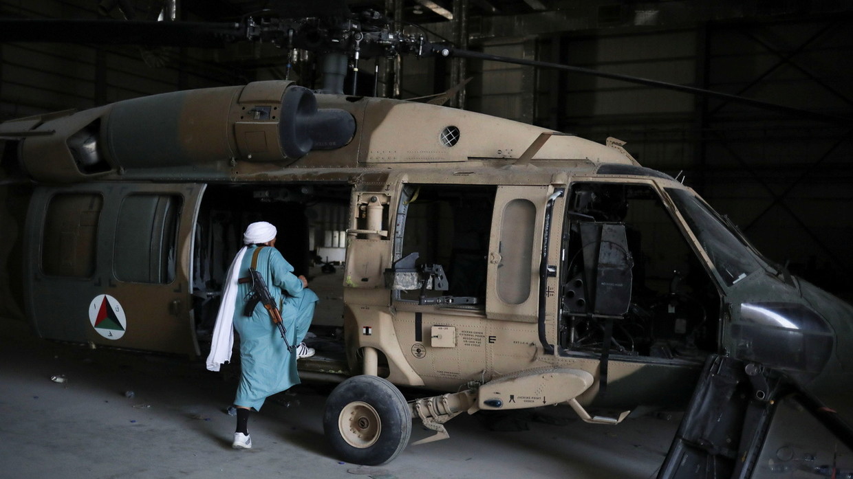 Một tay súng Taliban kiểm tra máy bay quân sự bị bỏ lại ở căn cứ Bagram.